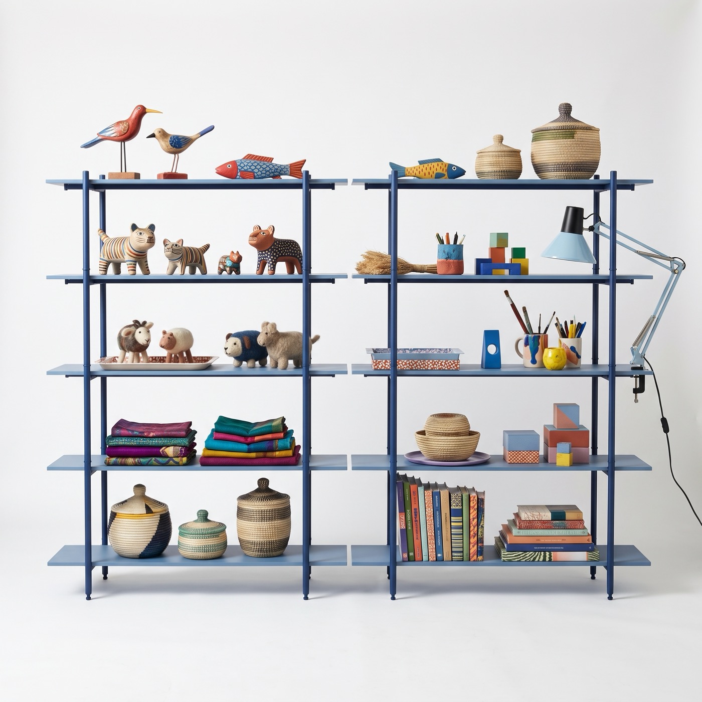 A wide two-bay shelf in marine blue steel holding books, baskets, carved wooden animals and a lamp.